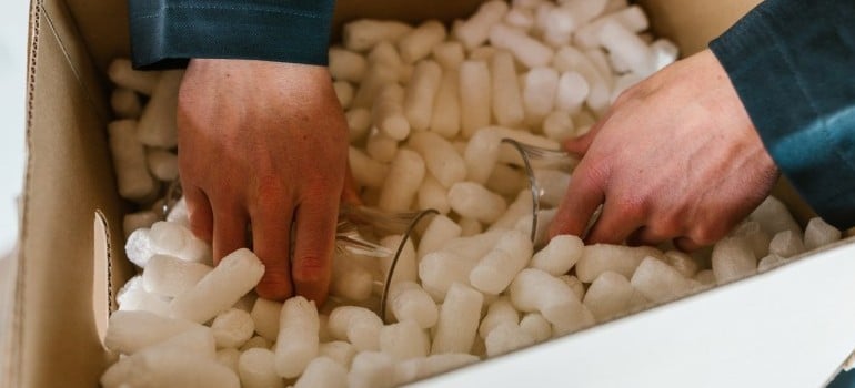 person packing glasses in packing peanuts