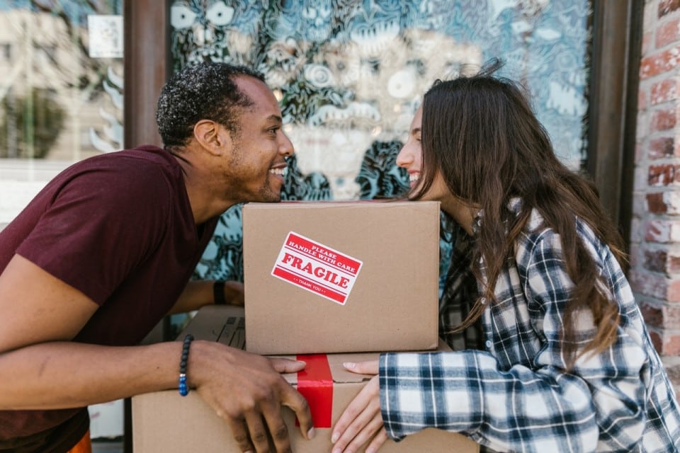 a young couple moving taking a break and looking at each other over a moving box