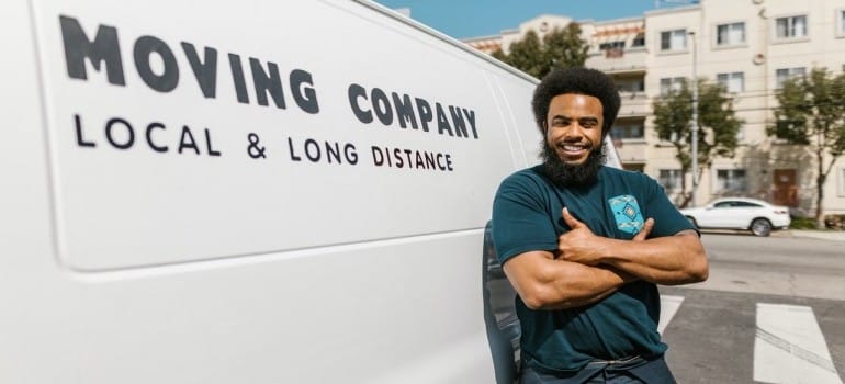 A mover posing in front of his moving van
