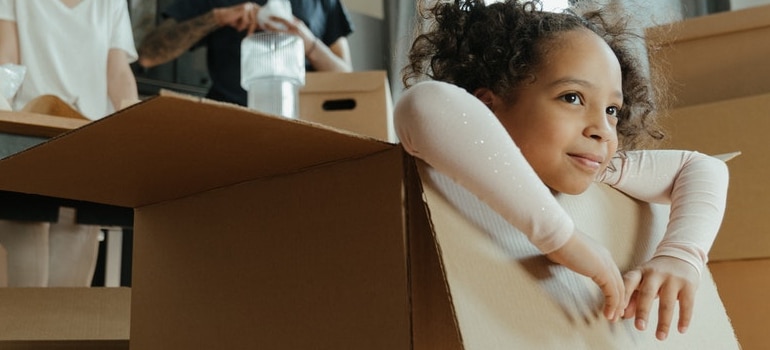 a girl playing in a cardboard box as a way to include kids in your cross-country move