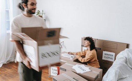 man carrying boxes and woman packing them