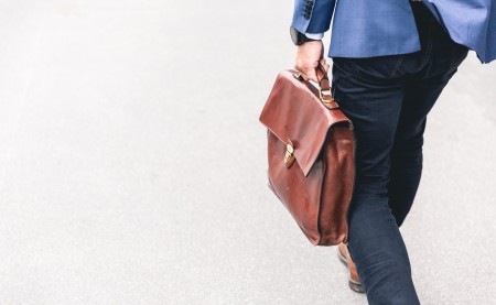 Businessman walking and holding a brown leather bag