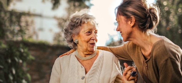 A daughter thinking about helping seniors deal with homesickness while hugging her mother