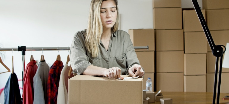 Woman packing and thinking of the hidden costs of moving that can happen