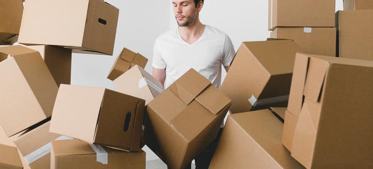 Man surrounded by boxes thinking of hiring long distance movers Ottawa