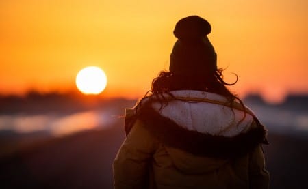a girl in a jacket and hat looking at the sunset in Regina, Canada