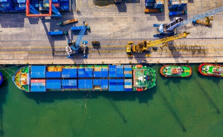 a birds-eye view of a ship loading containers in the dock