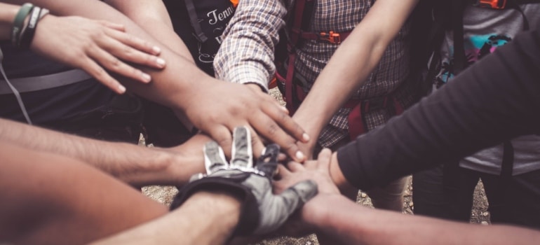 people putting hands together to show teamwork and sense of community