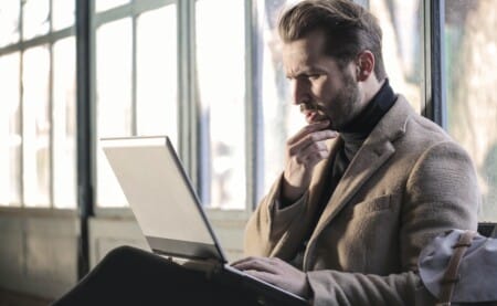 a man looking at his laptop while thinking