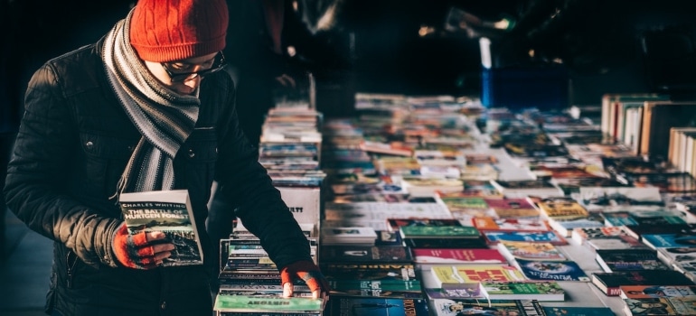 a man browsing through a variety of books on a pile