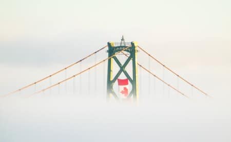 a picture of a bridge in Halifax, rising above the clouds