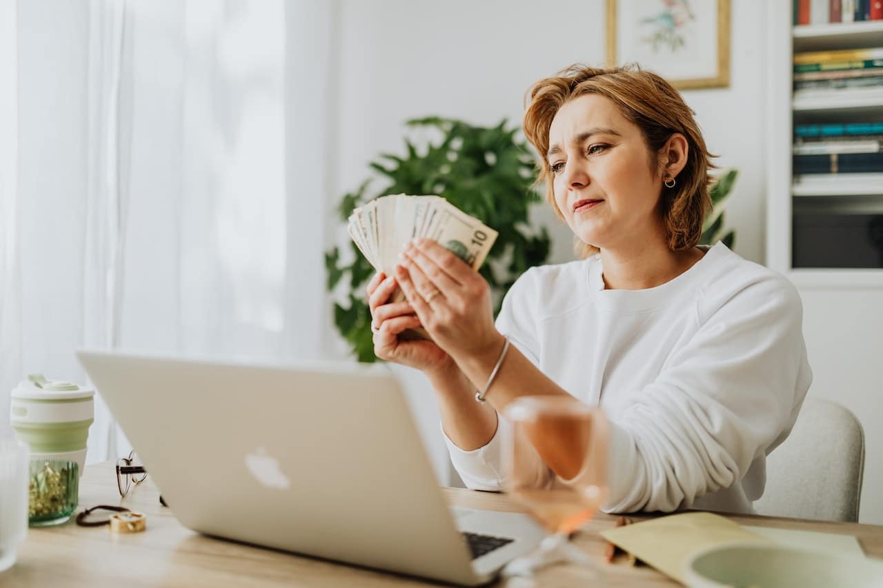 a woman counting money while sitting in her home office