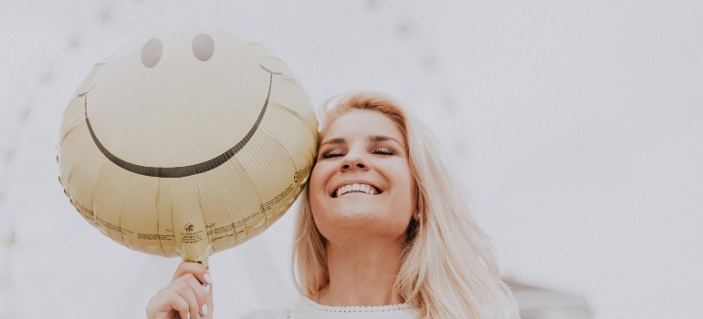 woman holding a smiley balloon 
