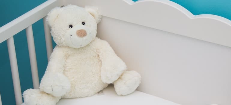 white teddy bear in baby's bed
