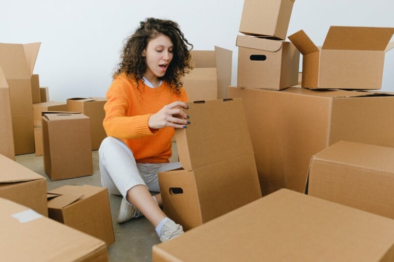 woman sitting among the cardboard boxes looking shocked
