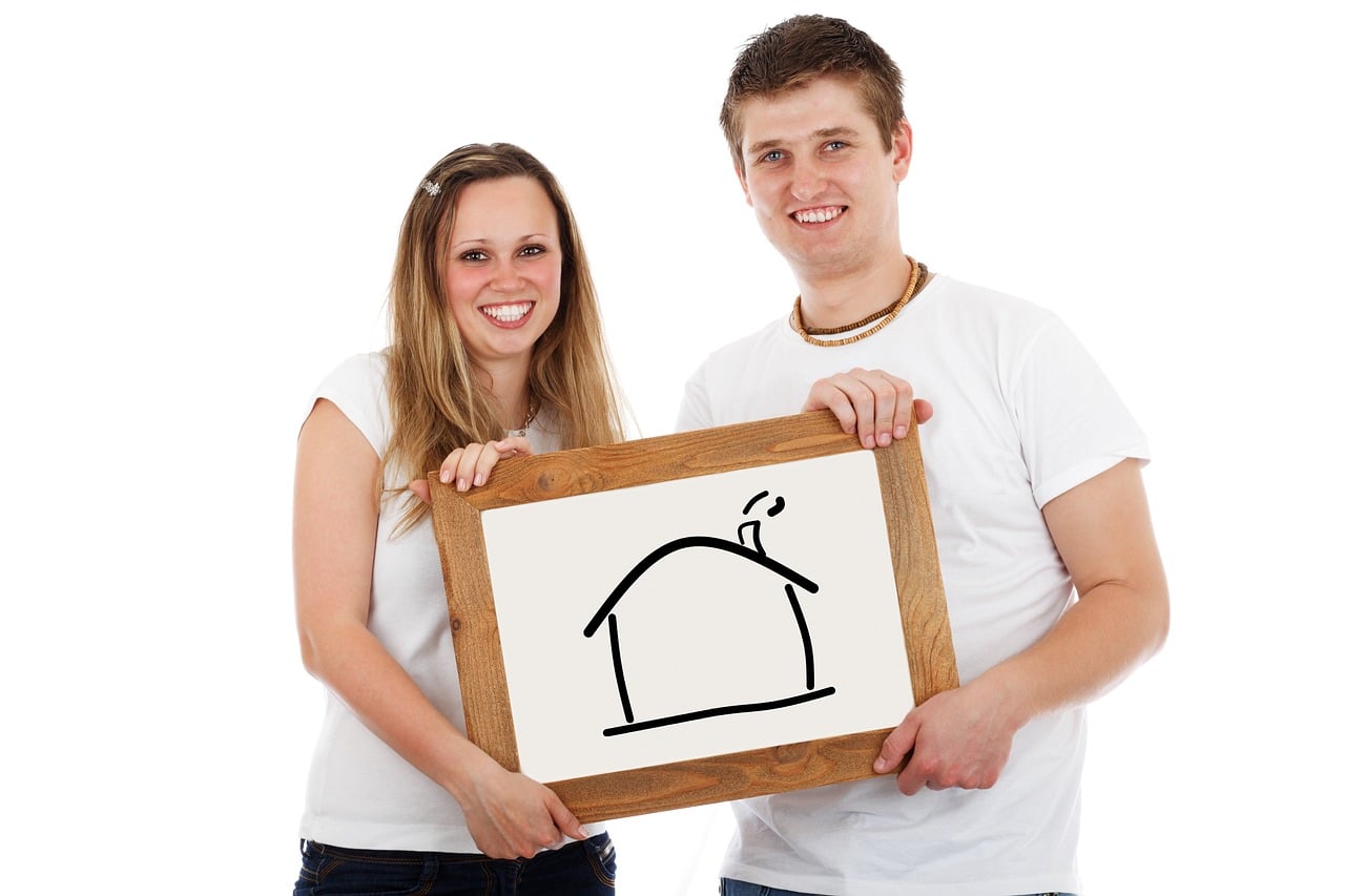 smiling couple holding a drawing of a house