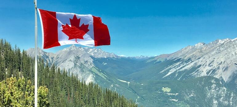 A flag of Canada in a mountain range that you can check out after moving from Toronto to Victoria