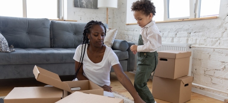 woman and boy packing items in cardboard boxes in accordance with our Moving while pregnant - a comprehensive guide