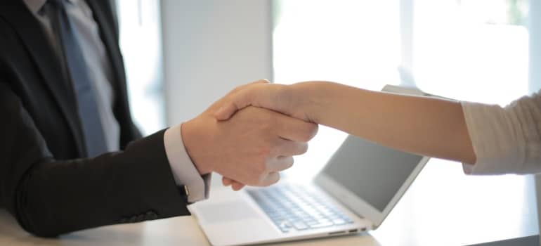 two persons shaking hands at the desk
