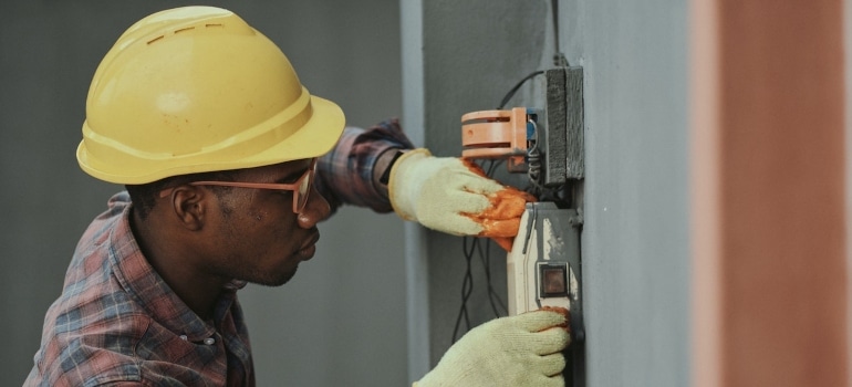 handyman with yellow helmet repairing the fuse box
