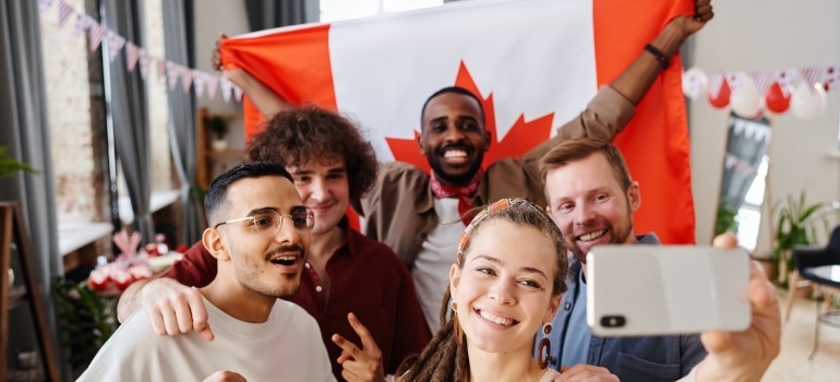 people taking a selfie in front of Canadian flag