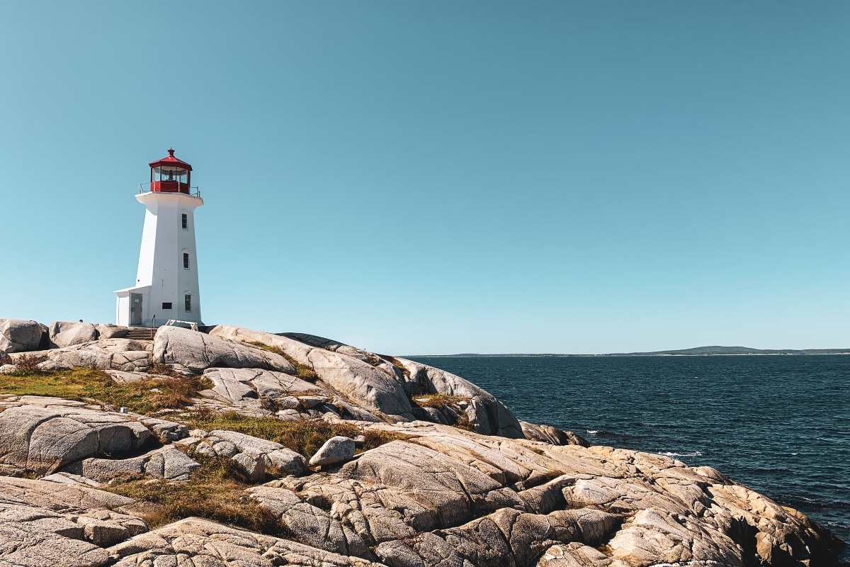 white lighthouse on brown rocky shore