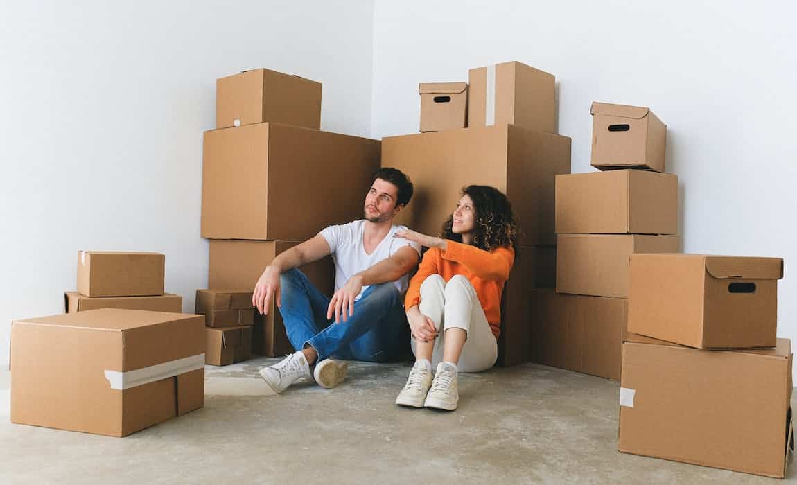 a couple sitting on the floor among many boxes