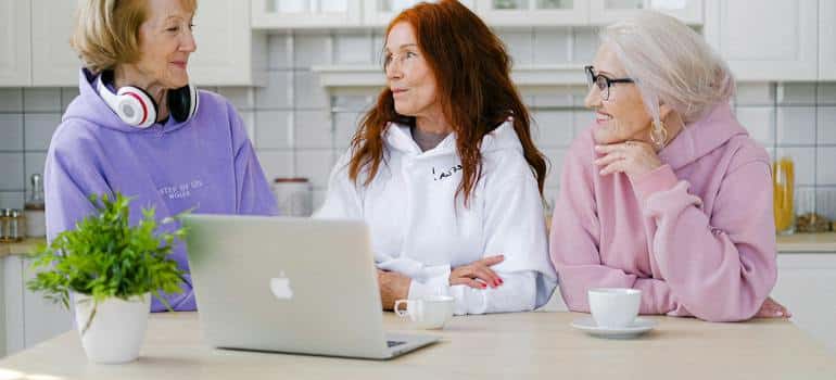 Positive senior women standing at table in kitchen and communicating