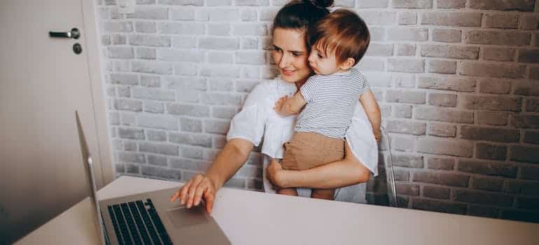 Mom holding a baby and working on a laptop