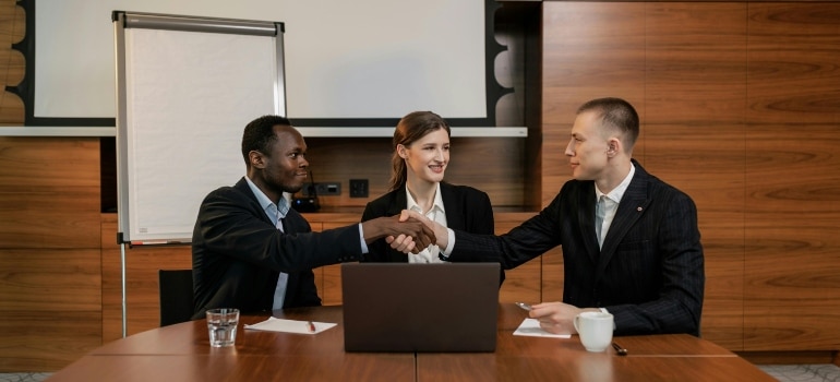 Business professionals shaking hands in a boardroom after successful negotiation.