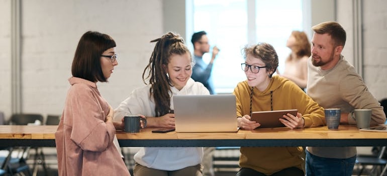 people talking to each other while sitting around a wooden desk