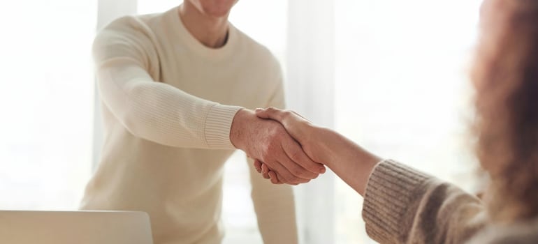 A friendly handshake in soft daylight captures the excitement of Starting a New Job in Montreal After Moving From Kingston.