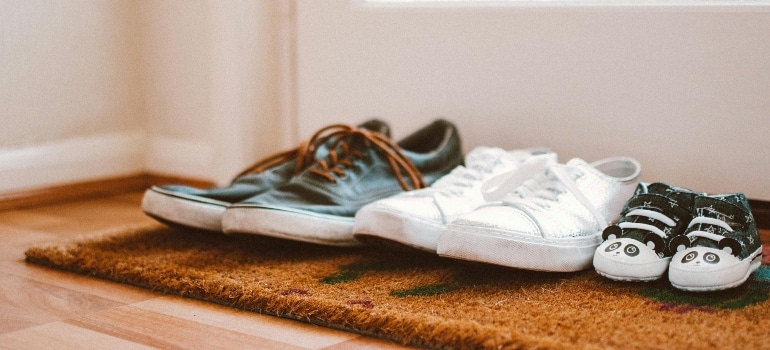 Three pairs of shoes at the front door of a home.