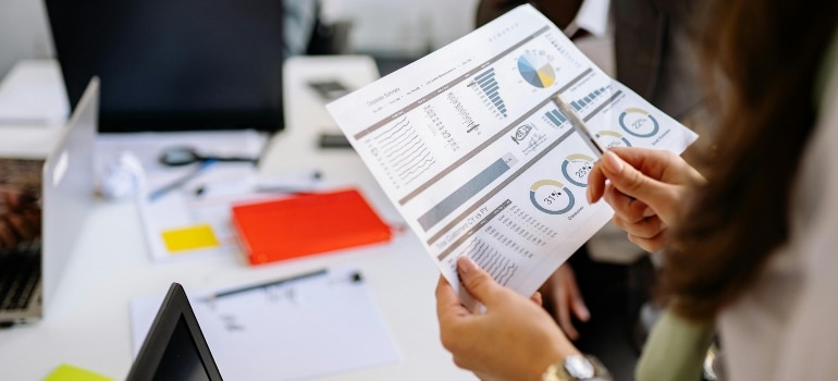 Team members discuss business growth charts and marketing stats in a modern office.