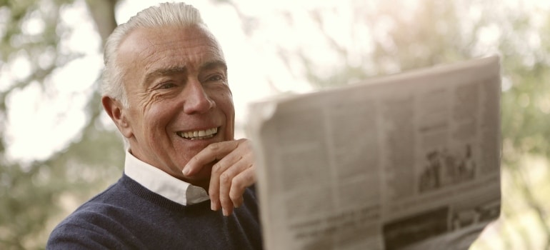Person smilig while reading newspapers before moving from Montreal to Vancouver