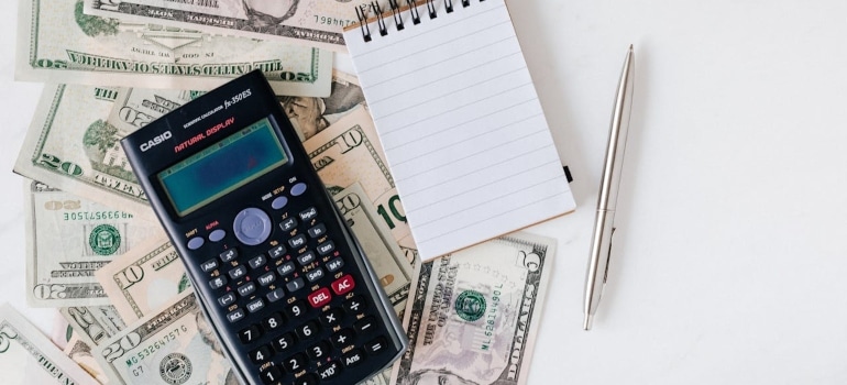 Calculator, notepad and pen on money