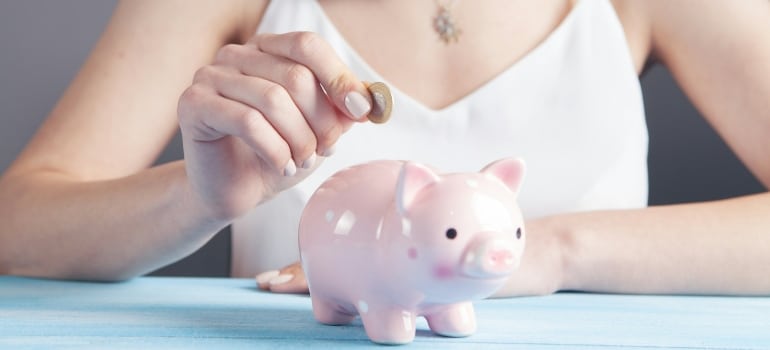 Person putting a coin in a piggy bank