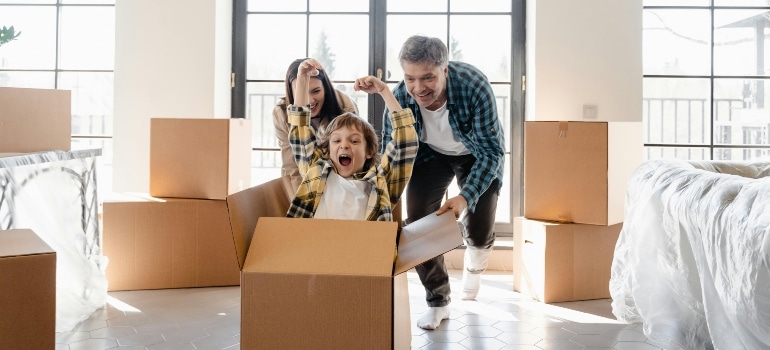 A family laughing and playing with their child in a moving box, celebrating Moving Without Regrets.